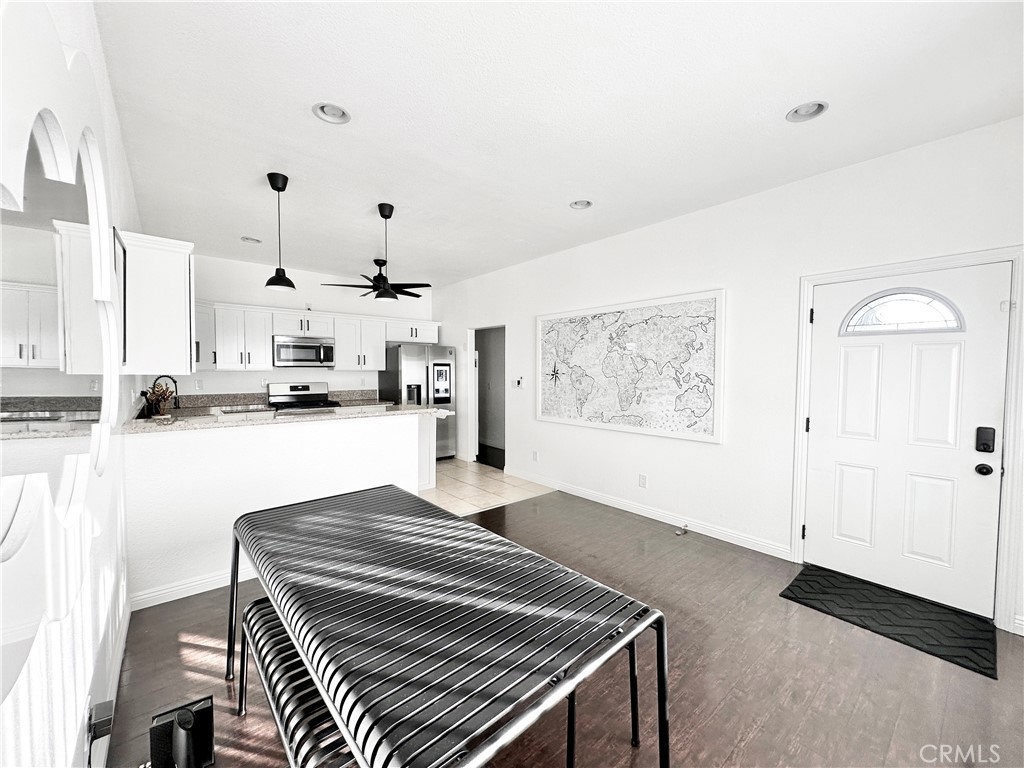 a living room with stainless steel appliances lots of wooden furniture and view of kitchen