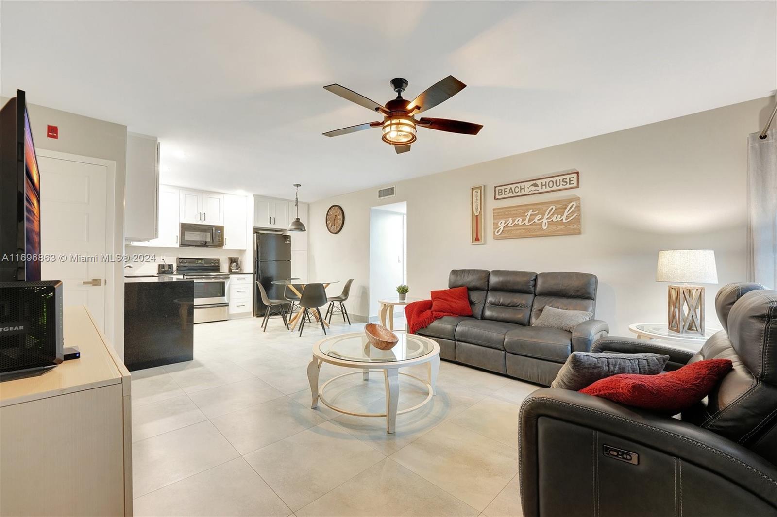 a living room with furniture a flat screen tv and kitchen view