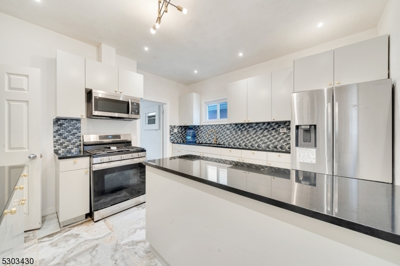 a kitchen with granite countertop a refrigerator and a stove top oven