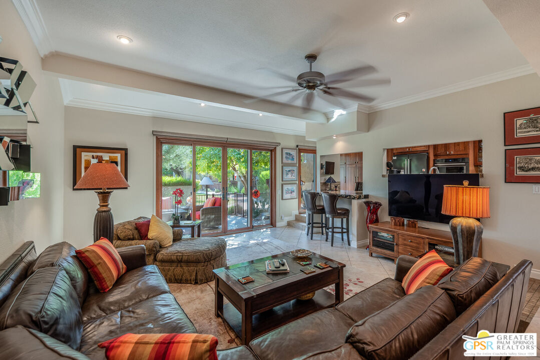 a living room with furniture a ceiling fan and a flat screen tv