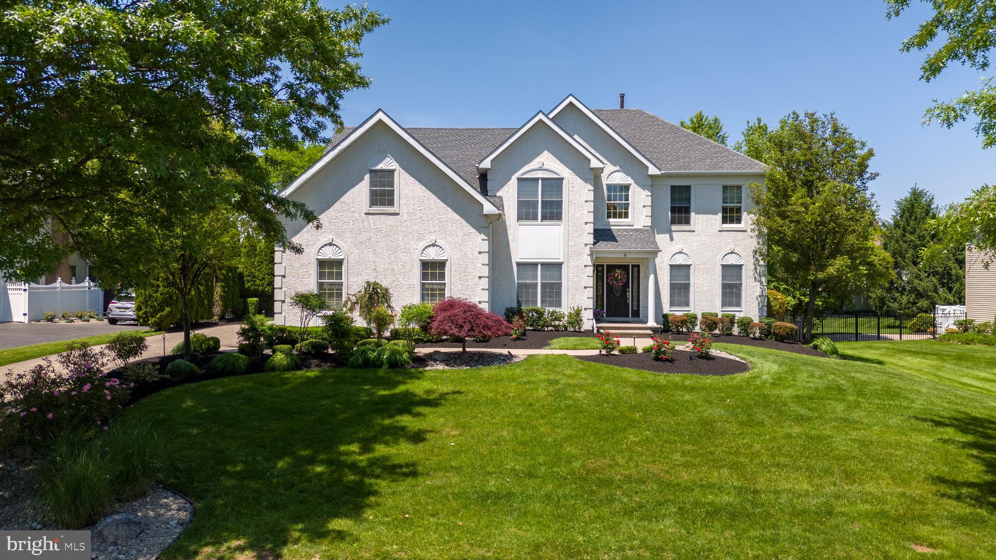 a front view of a house with garden and trees