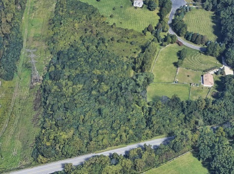 an aerial view of residential house with outdoor space and trees all around