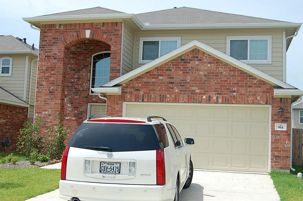 a view of a house with a small yard and a car parked in front of it