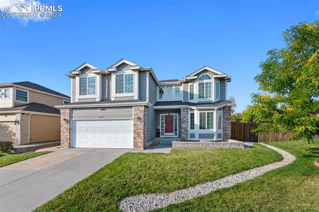 View of front of property with a front yard and a garage