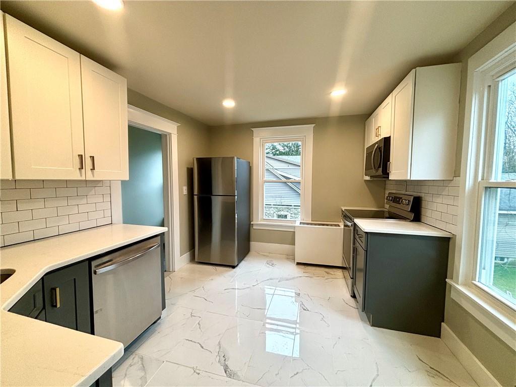 Kitchen featuring white cabinets, stainless steel appliances, and tasteful backsplash