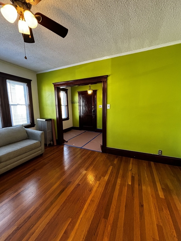 a view of a room with wooden floor a ceiling fan and windows