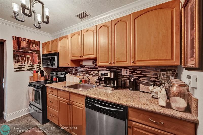 a kitchen with stainless steel appliances granite countertop a sink a stove and a microwave