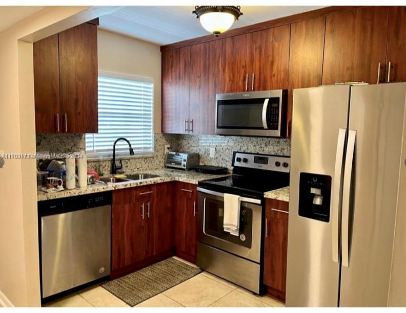 a kitchen with stainless steel appliances granite countertop wooden cabinets a stove top oven a sink and dishwasher