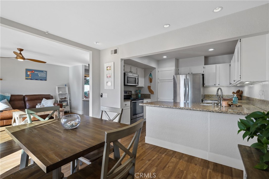 a kitchen with stainless steel appliances kitchen island granite countertop a dining table chairs and granite counter tops