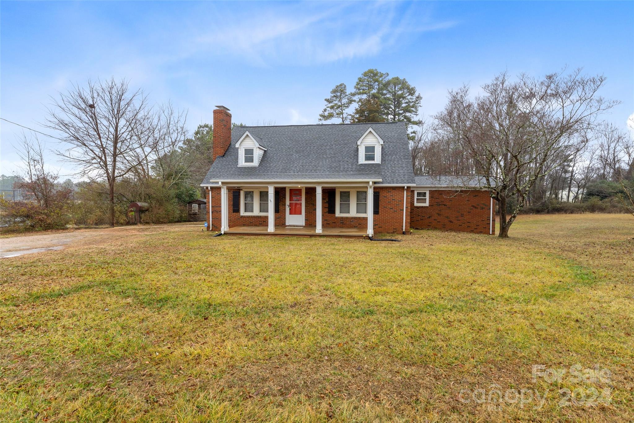 a front view of house with yard and trees in the background