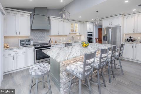 a kitchen with stainless steel appliances kitchen island granite countertop a sink a stove a refrigerator cabinets and chairs