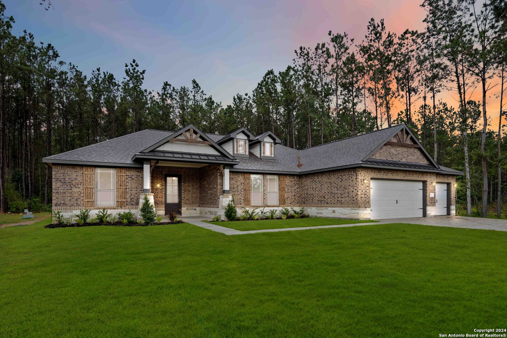 a front view of a house with a garden and trees