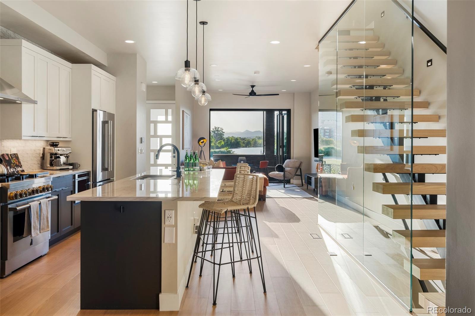 a view of a kitchen with kitchen island granite countertop a large window a sink stainless steel appliances and cabinets