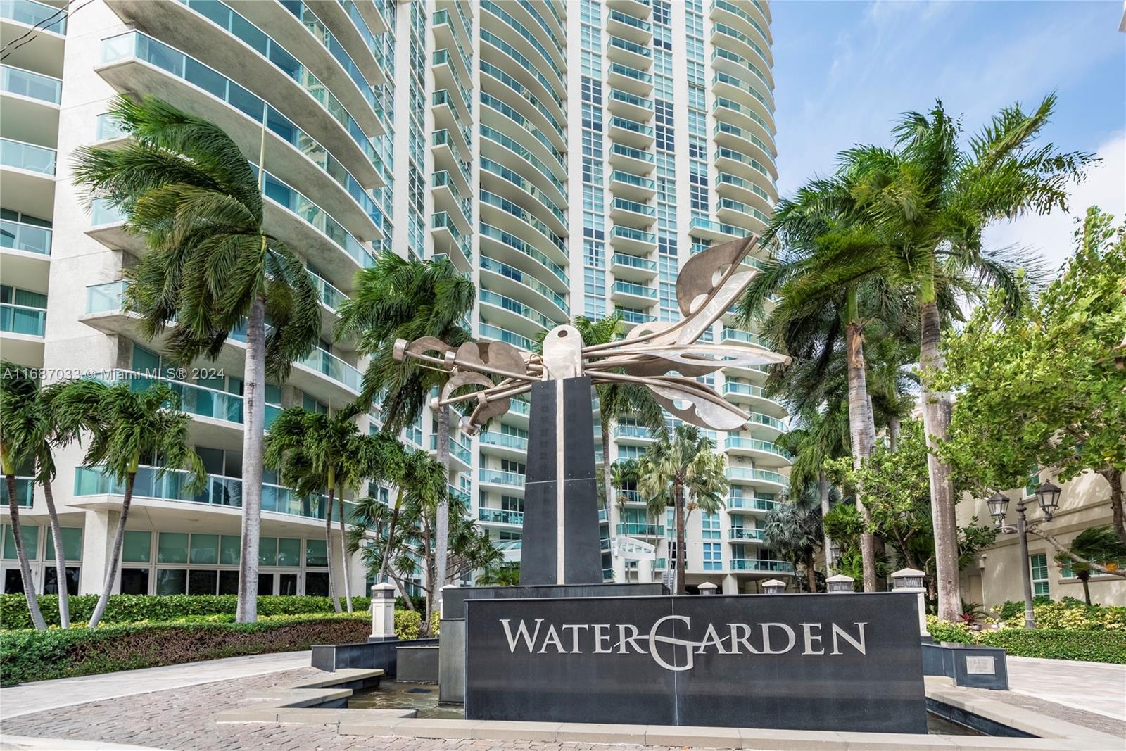 a front view of multi story residential apartment building with yard and sign board