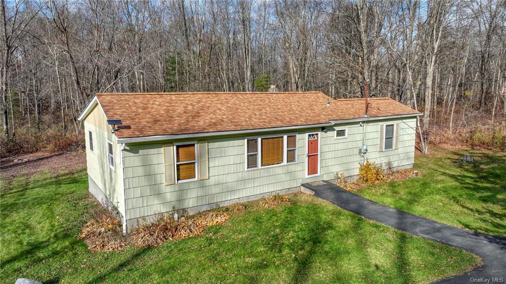 a aerial view of a house with yard and trees in the background