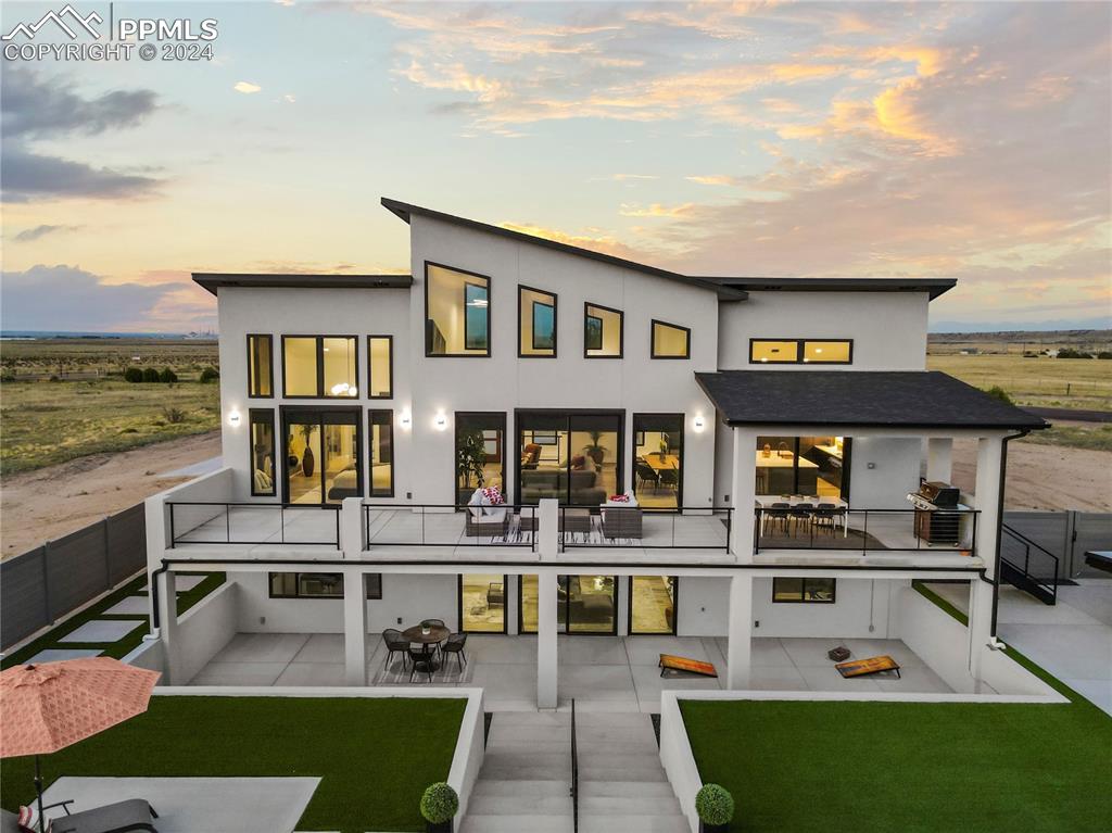 Back house at dusk featuring a multiple patio areas with faux lawn for easy care and maintenance