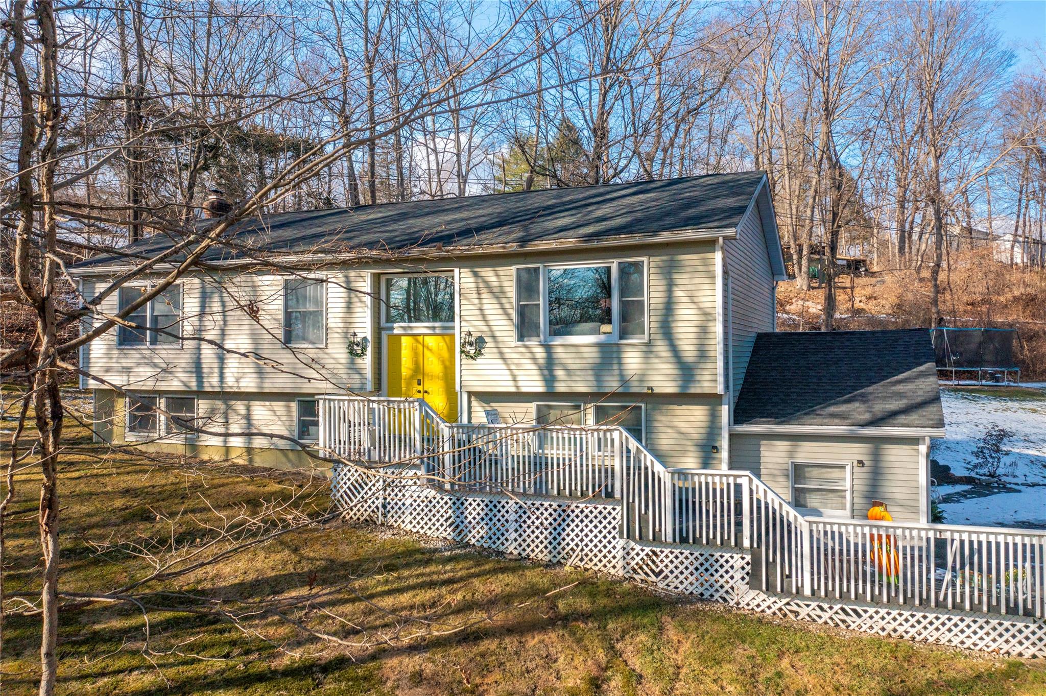 Raised ranch with a front yard, a trampoline, and a wooden deck