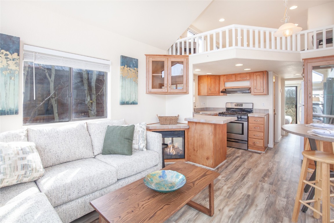 a living room with furniture a fireplace and a dining table with wooden floor