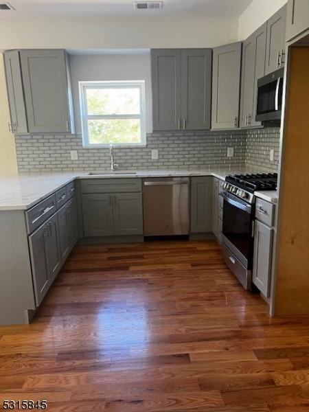 a kitchen with granite countertop wooden floors appliances and sink