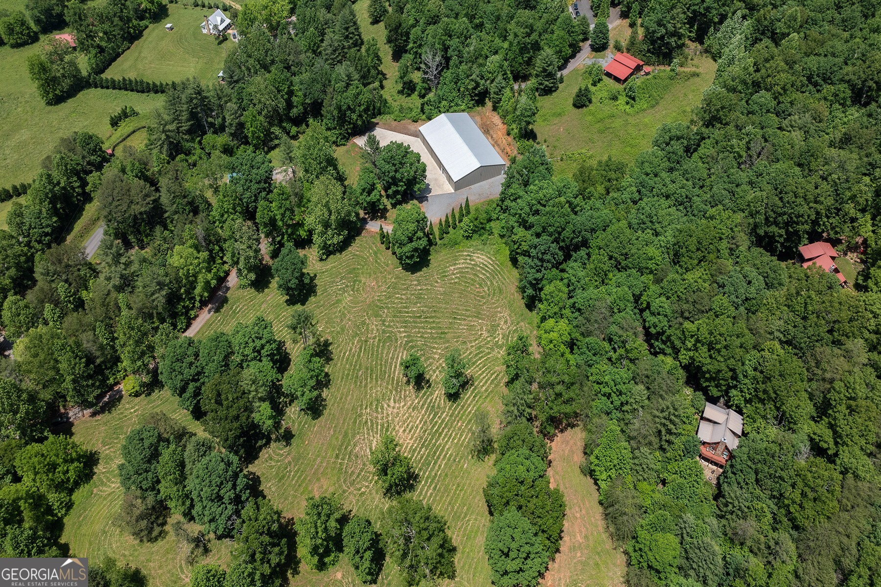 an aerial view of residential house with outdoor space and trees all around