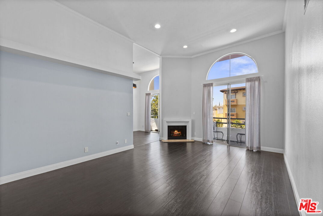 an empty room with wooden floor fireplace and windows