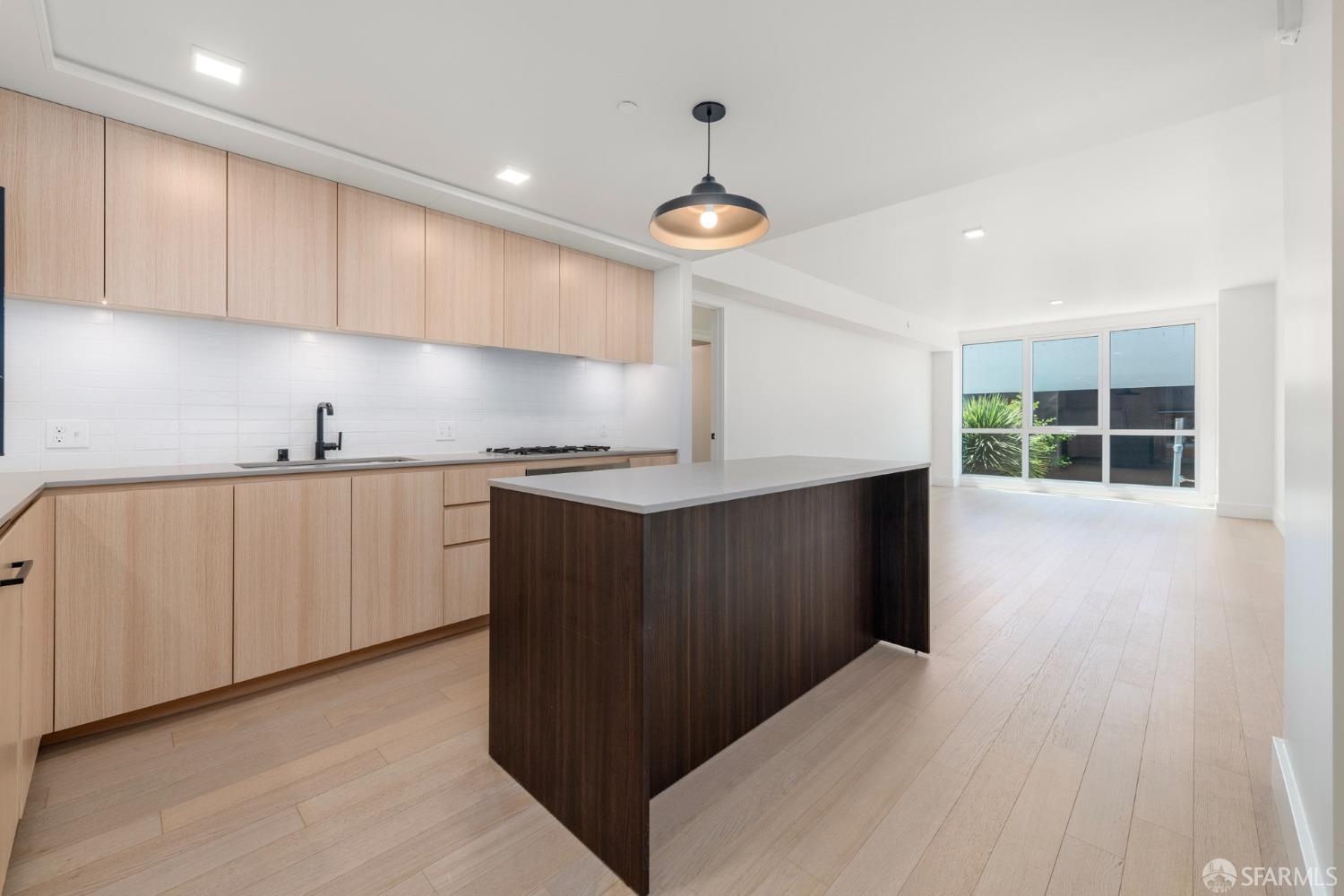 a kitchen with granite countertop a stove a sink and white cabinets with wooden floor