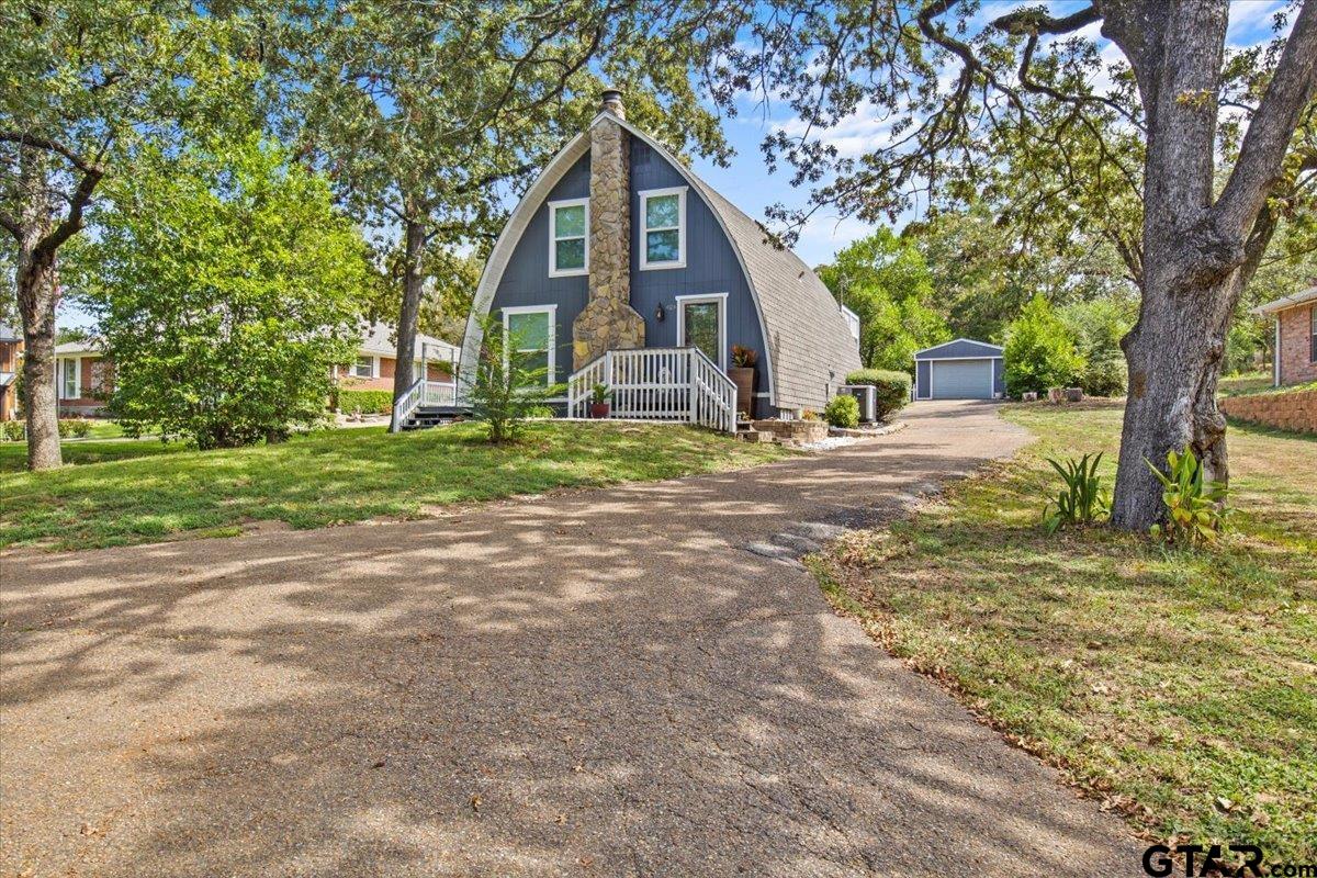 a view of a house with a yard and large trees