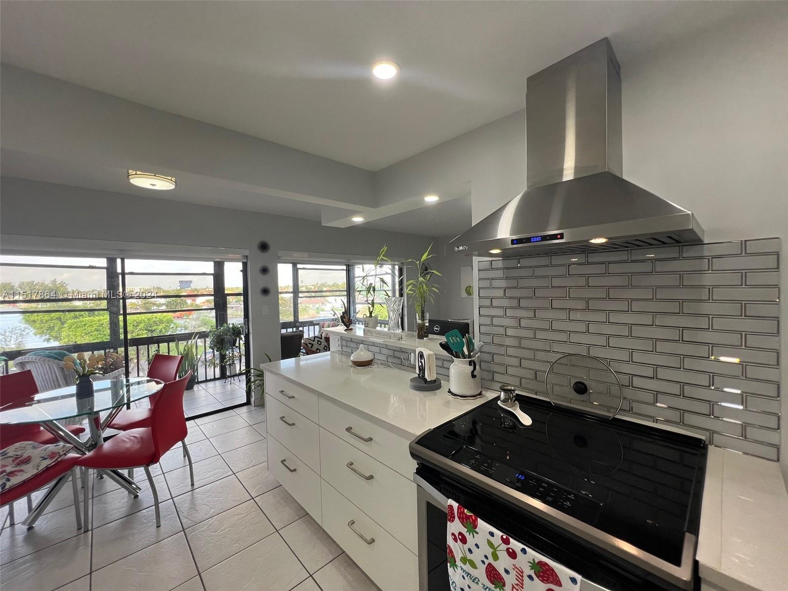 a kitchen with stainless steel appliances kitchen island granite countertop a stove a sink and a large window