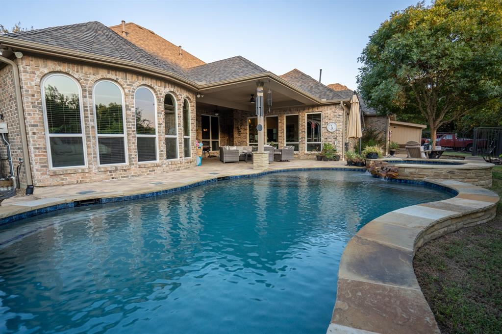 a front view of a house with swimming pool and porch with furniture