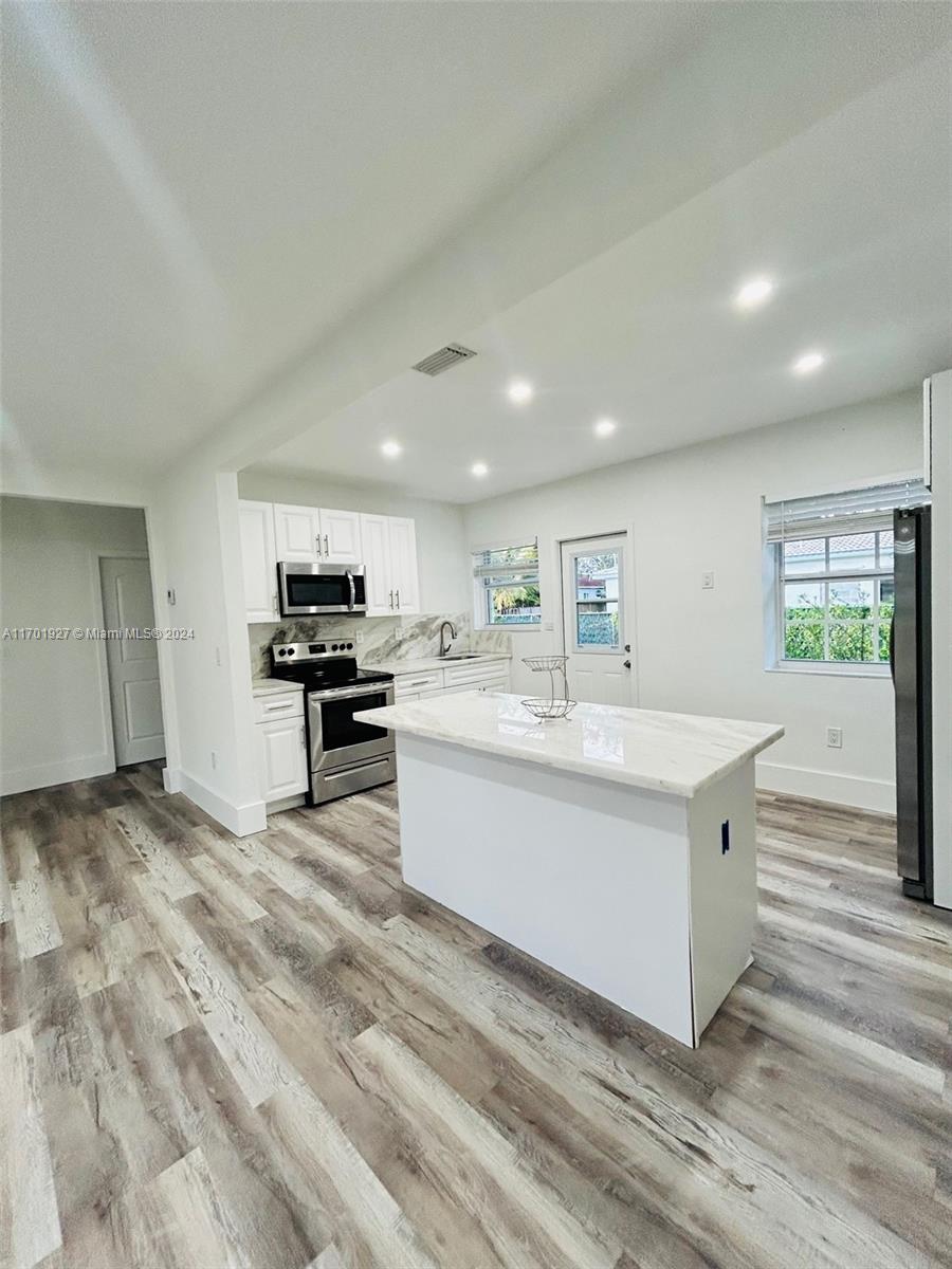 a large white kitchen with kitchen island a sink a stove and a refrigerator