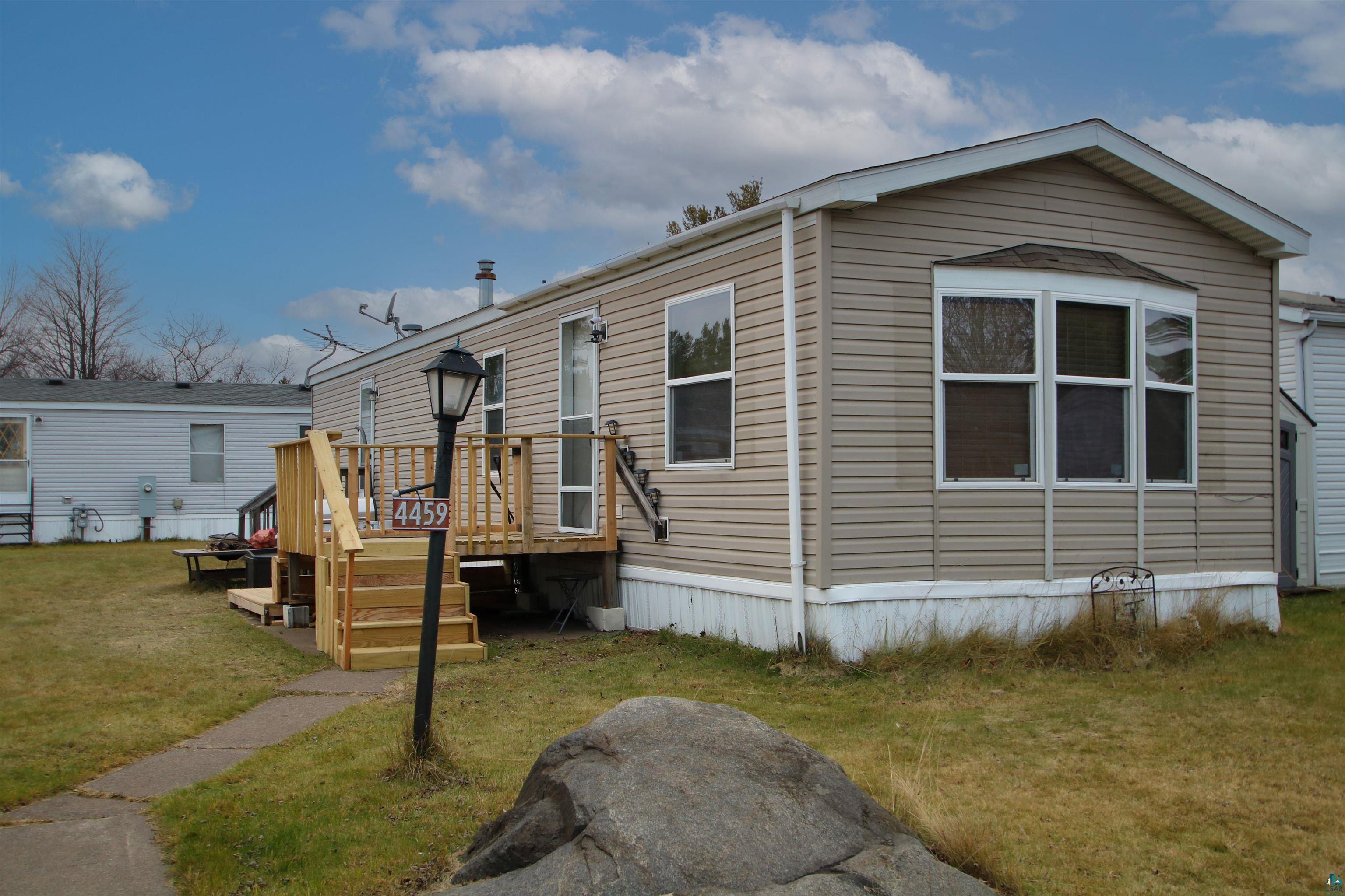 Manufactured / mobile home featuring a front lawn and a wooden deck