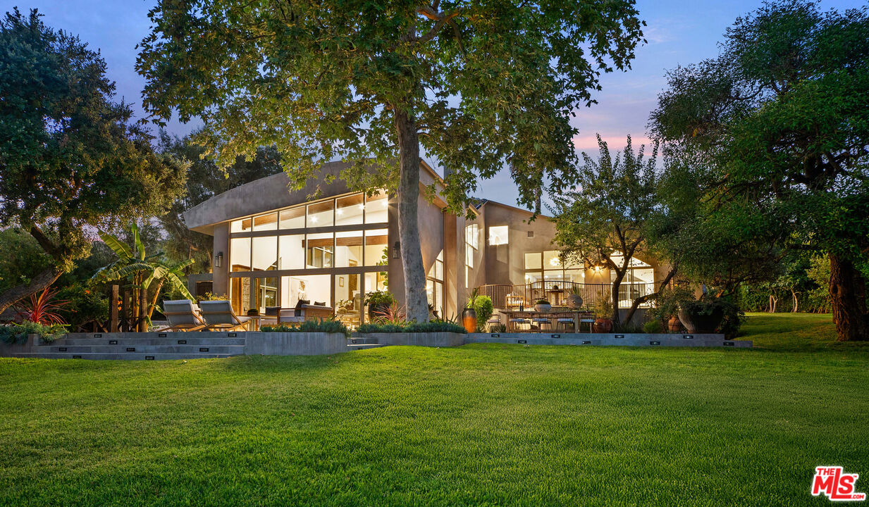 a view of a house with a big yard and large trees