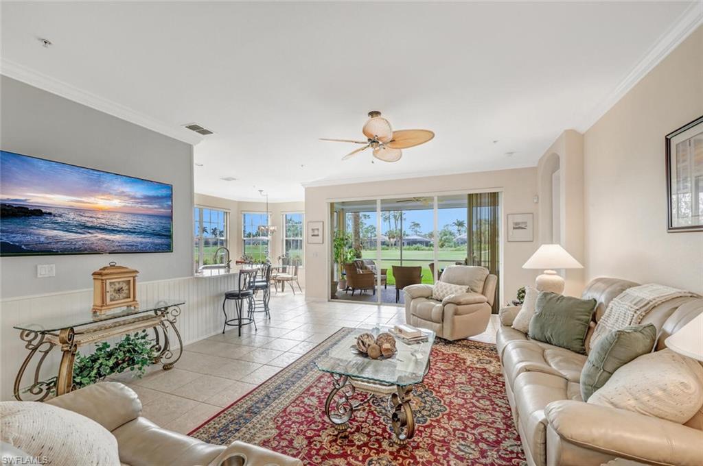 Tiled living room featuring ceiling fan and crown molding