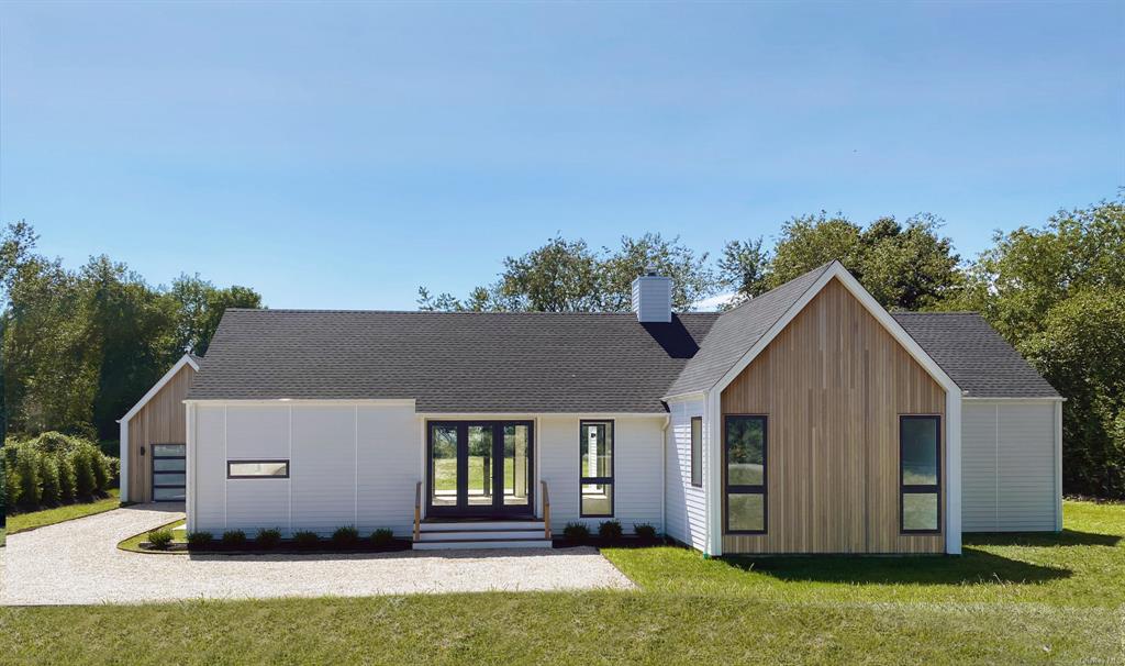 View of front of home with a front yard, a garage, and an outdoor structure