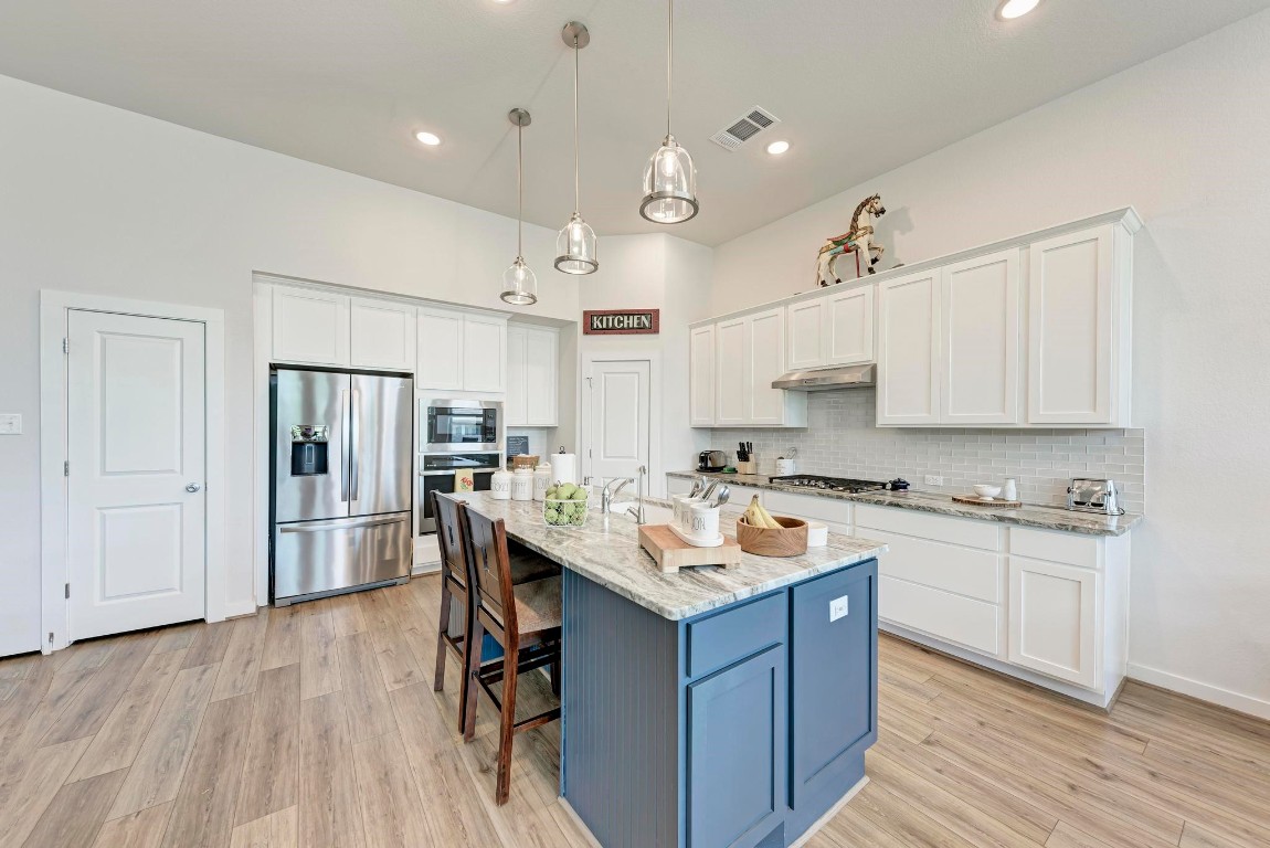 a kitchen with a stove a sink a refrigerator and white cabinets with wooden floor