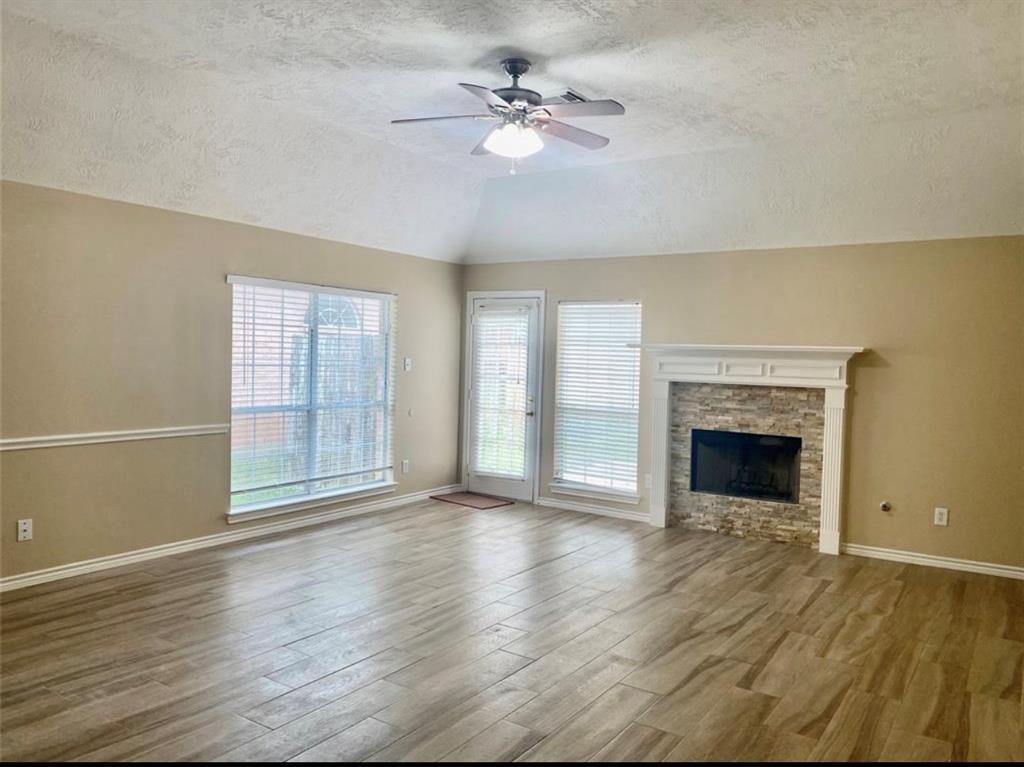 an empty room with windows fireplace and a kitchen view