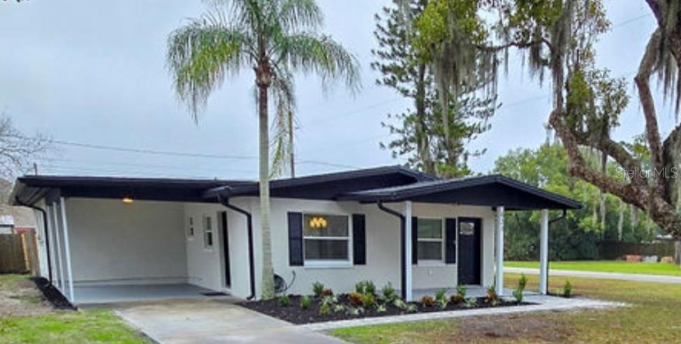 a view of a house with a yard and palm trees