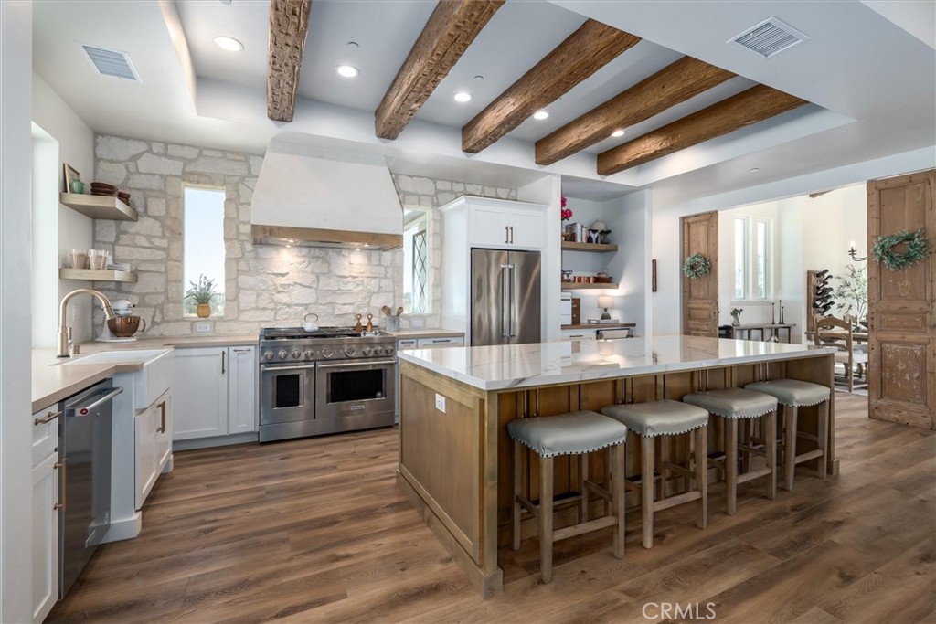 a kitchen with stainless steel appliances granite countertop a table chairs sink and cabinets