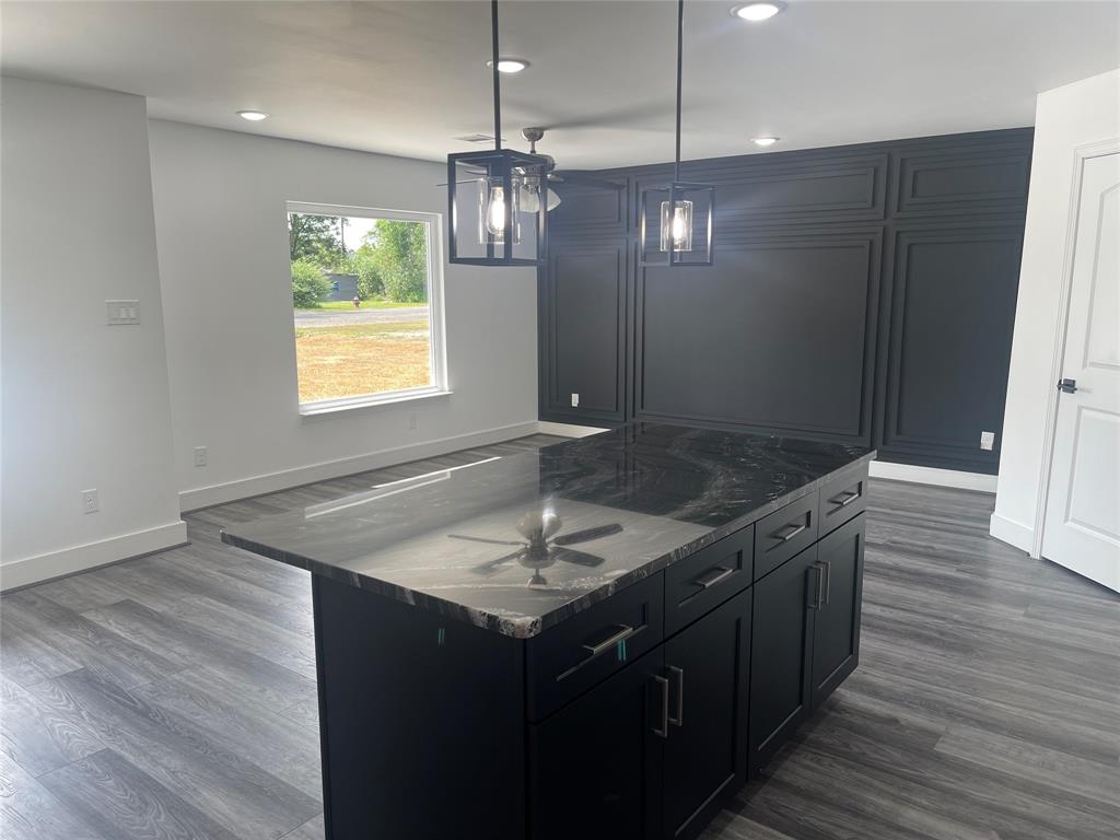 a kitchen with kitchen island granite countertop stainless steel appliances a sink stove and wooden floor