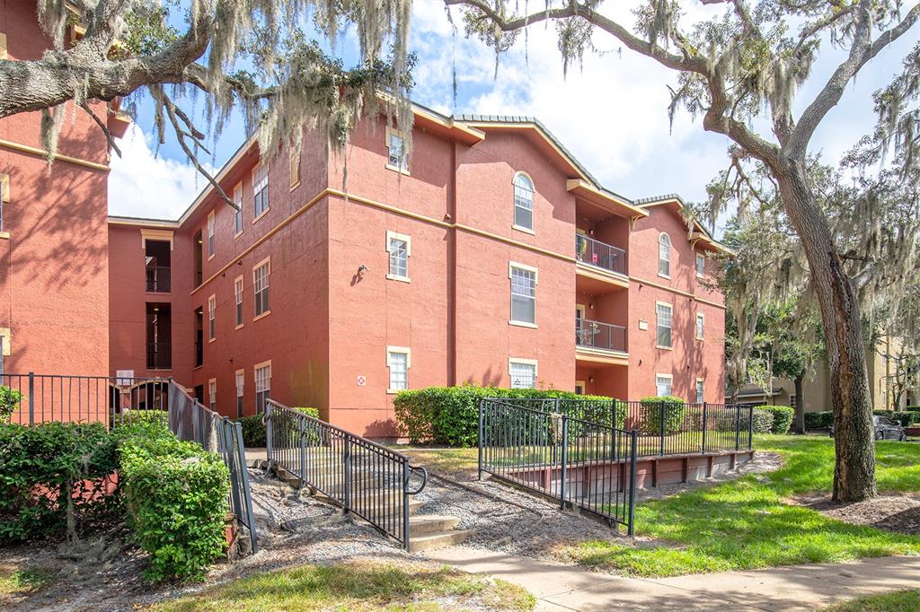 a view of a brick building next to a yard with big trees