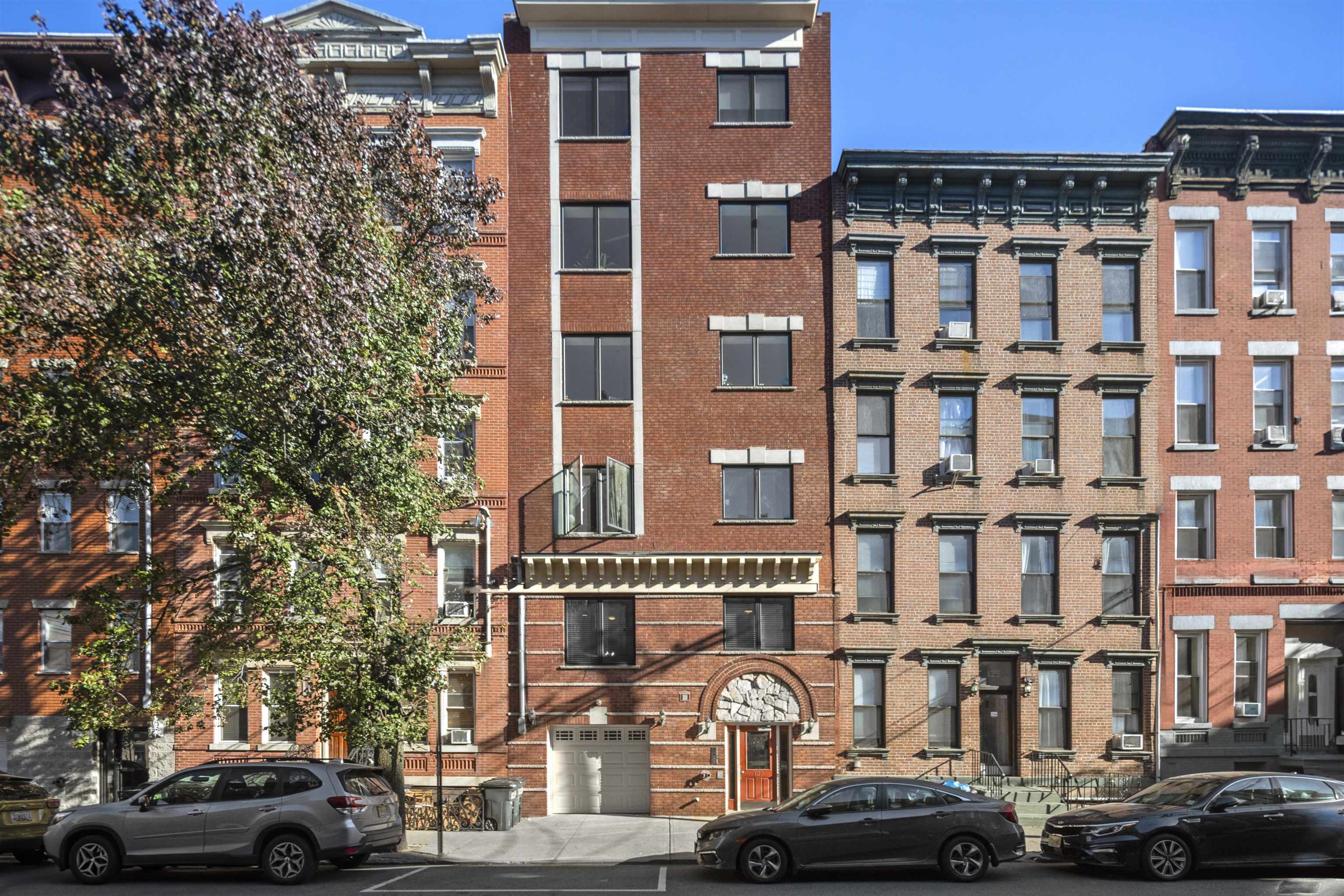 a front view of a building with lot of cars and trees