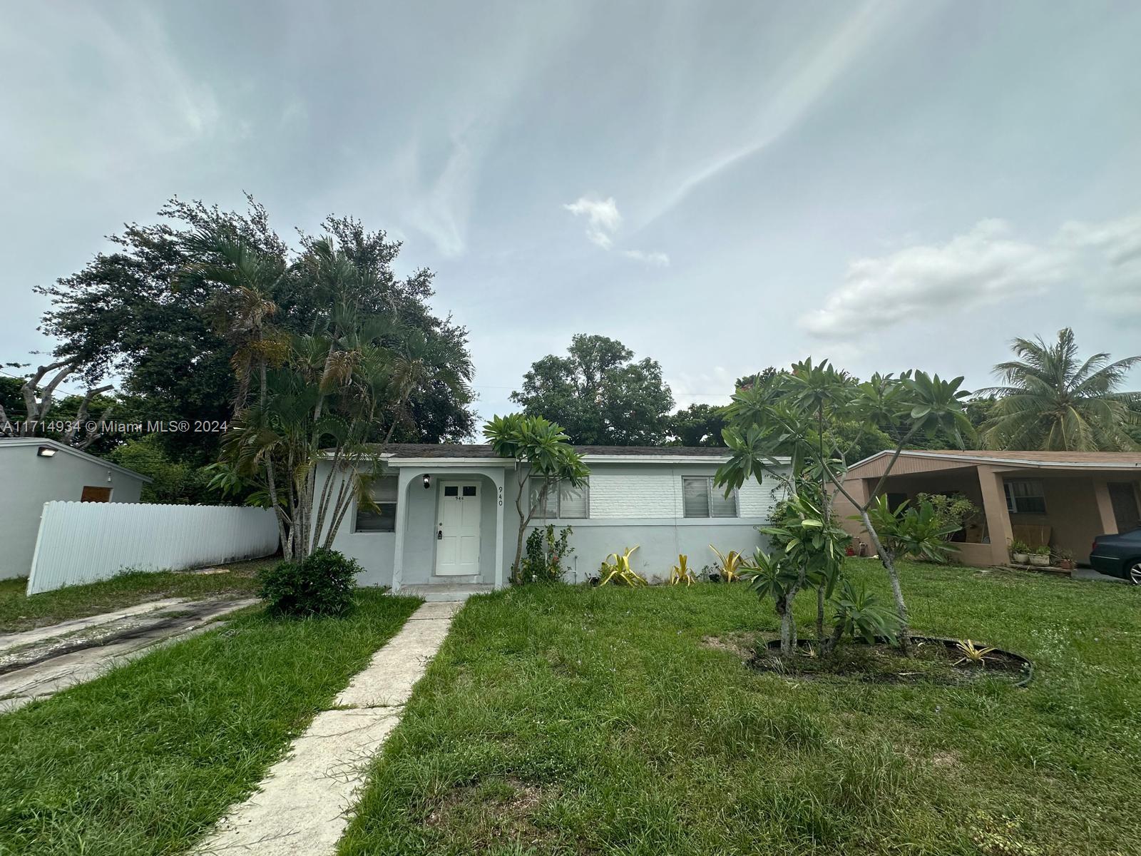 a front view of house with garden and trees