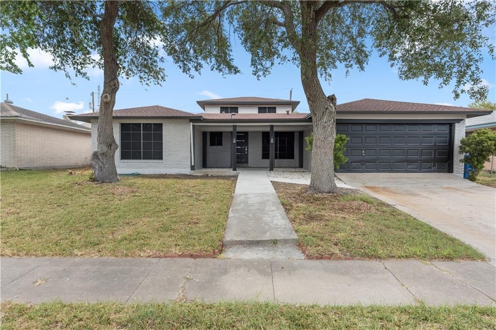 a front view of a house with yard and tree