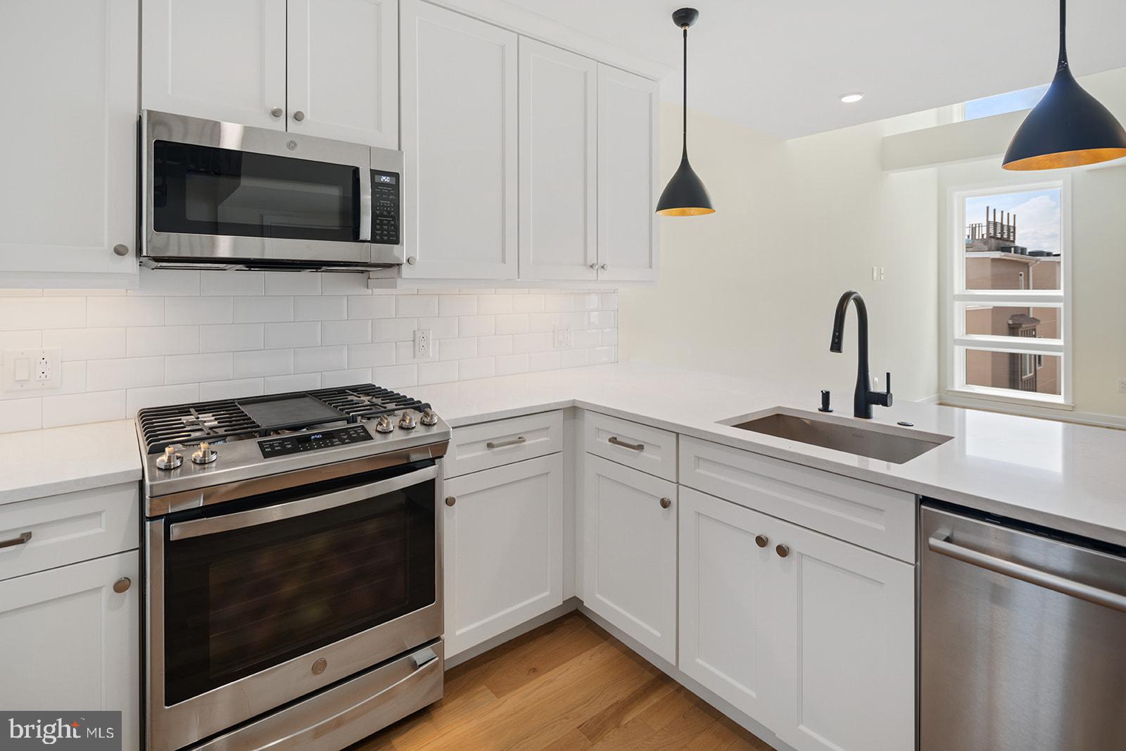 a kitchen with stainless steel appliances a stove a microwave and sink