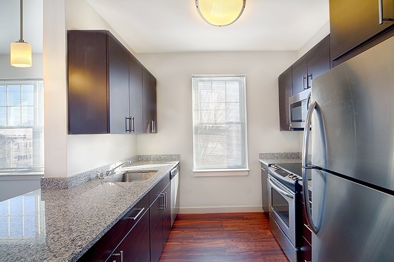 a kitchen with granite countertop a sink a stove and refrigerator