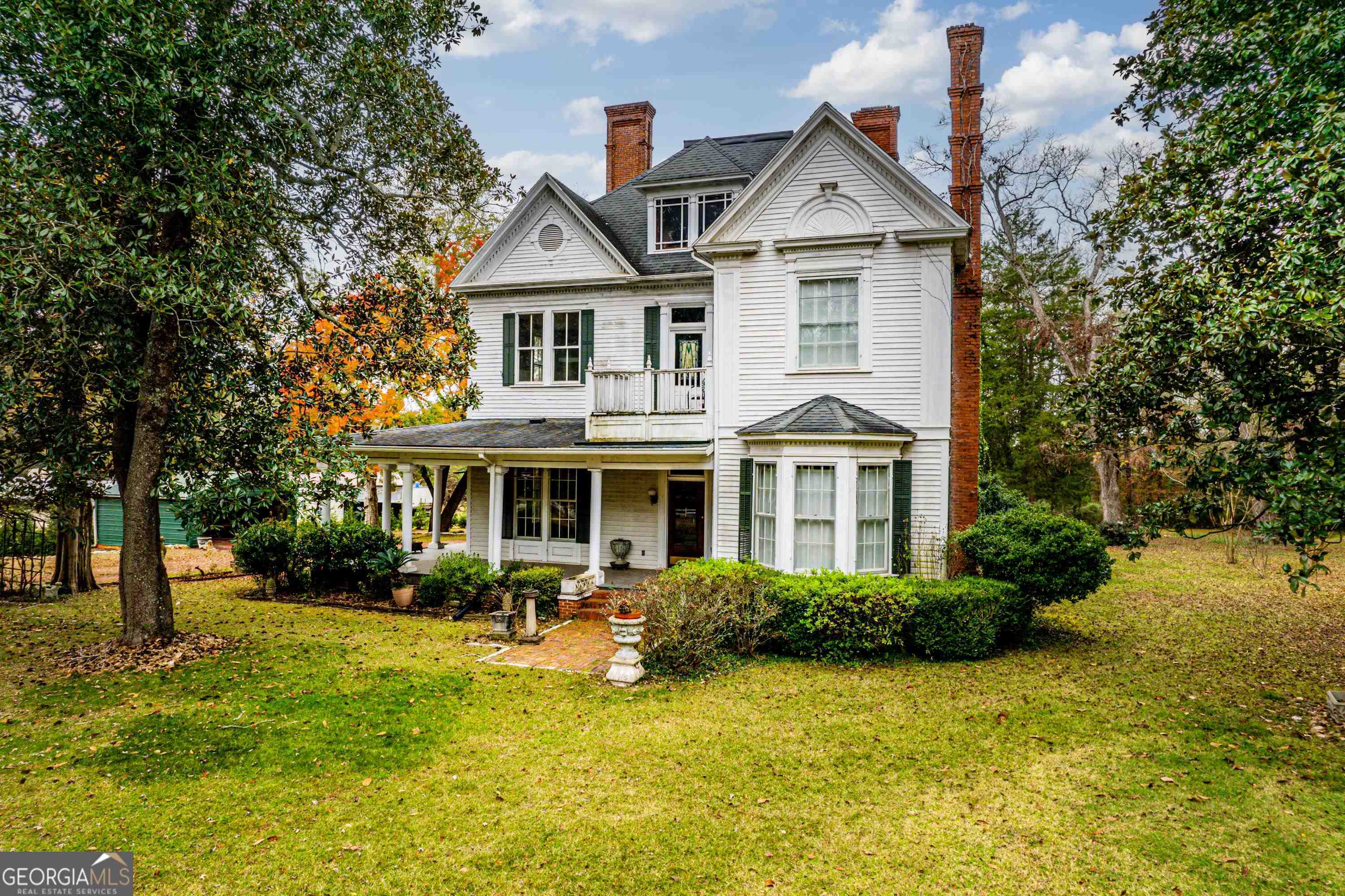 a front view of a house with garden and trees