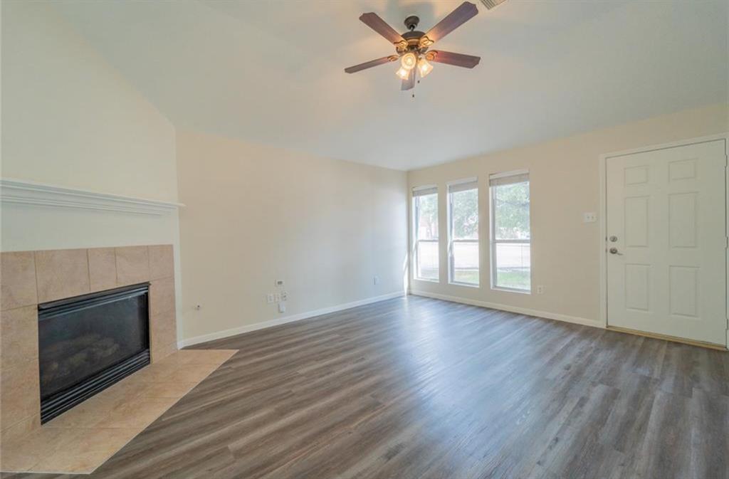 an empty room with wooden floor fireplace and fan