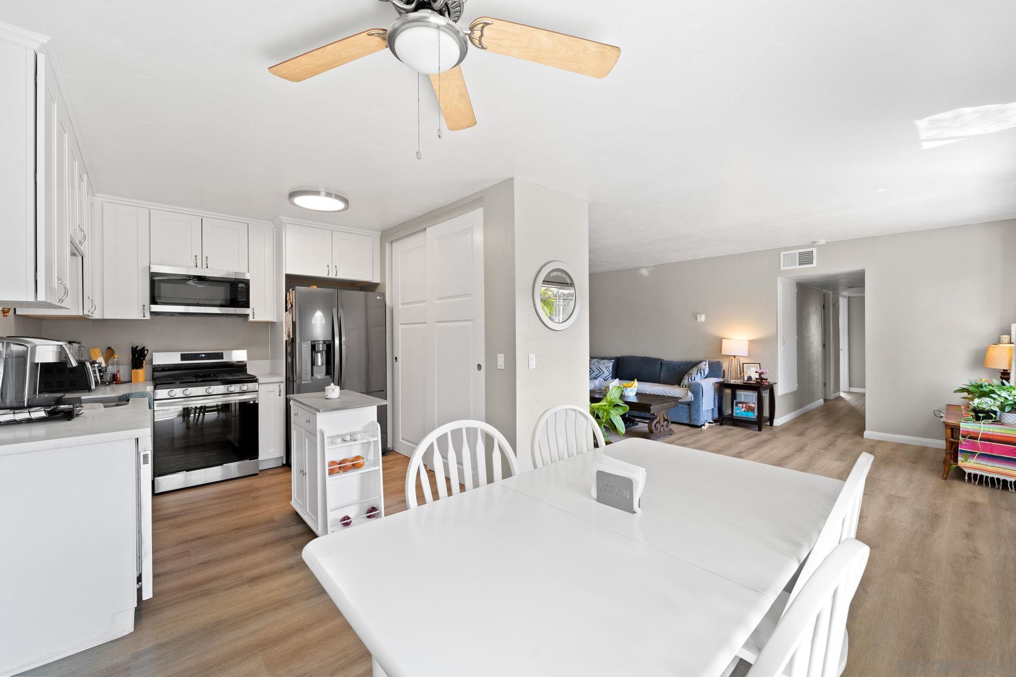 a kitchen with stainless steel appliances kitchen island granite countertop a refrigerator a stove top oven a sink dishwasher and white appliances with wooden floor