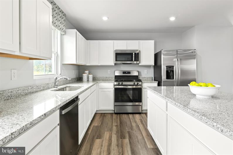 a kitchen with stainless steel appliances granite countertop a sink a stove top oven a counter space and cabinets