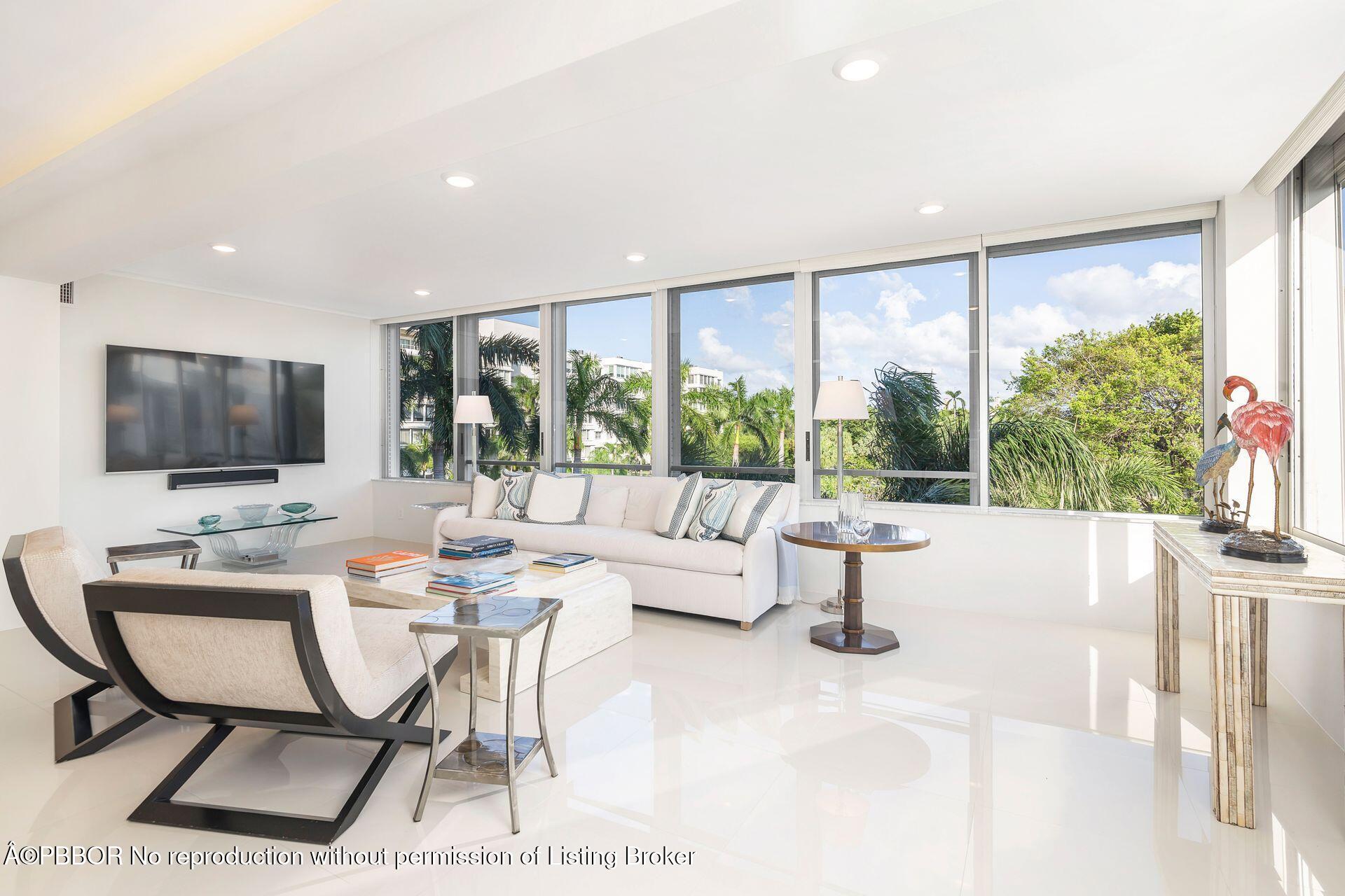 a living room with furniture a flat screen tv and a floor to ceiling window